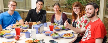 group of people smiling around a table with food