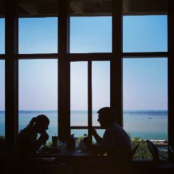 people eating in front of a window overlooking a body of water