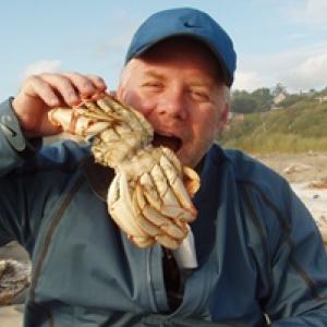 Richard pretends to eat a crab on a beach